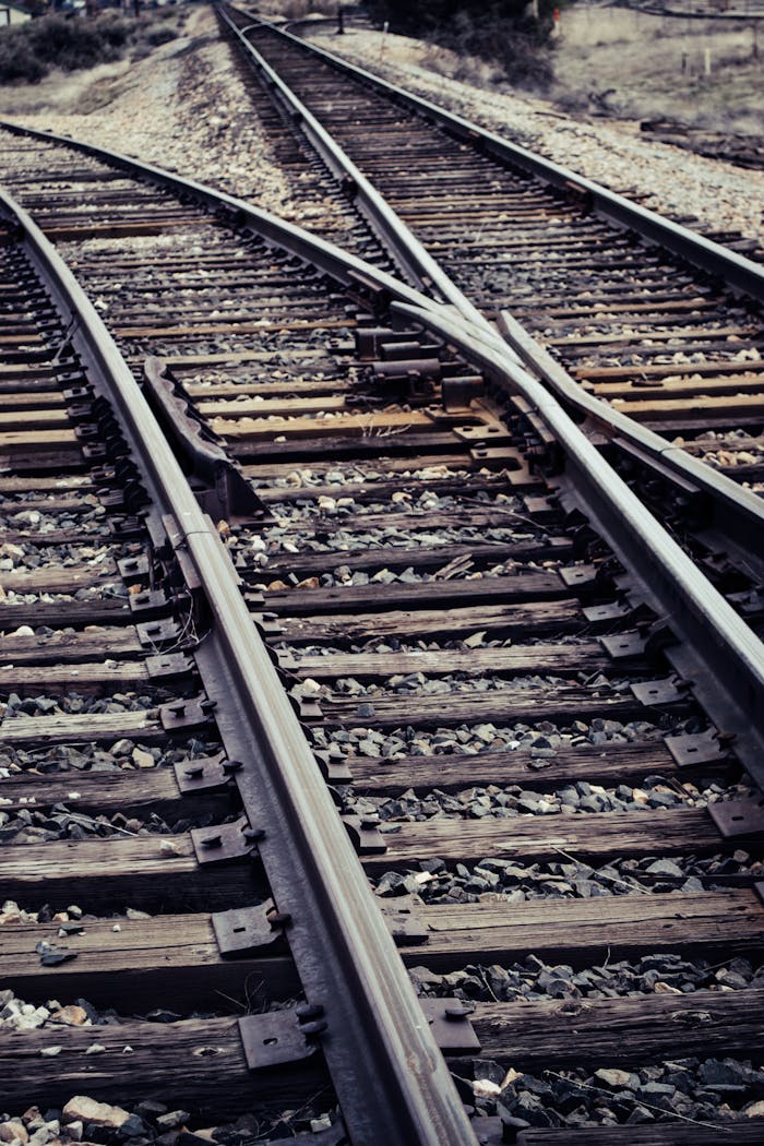Converging railway tracks photographed in an outdoor setting, showcasing metal rails and wooden ties.